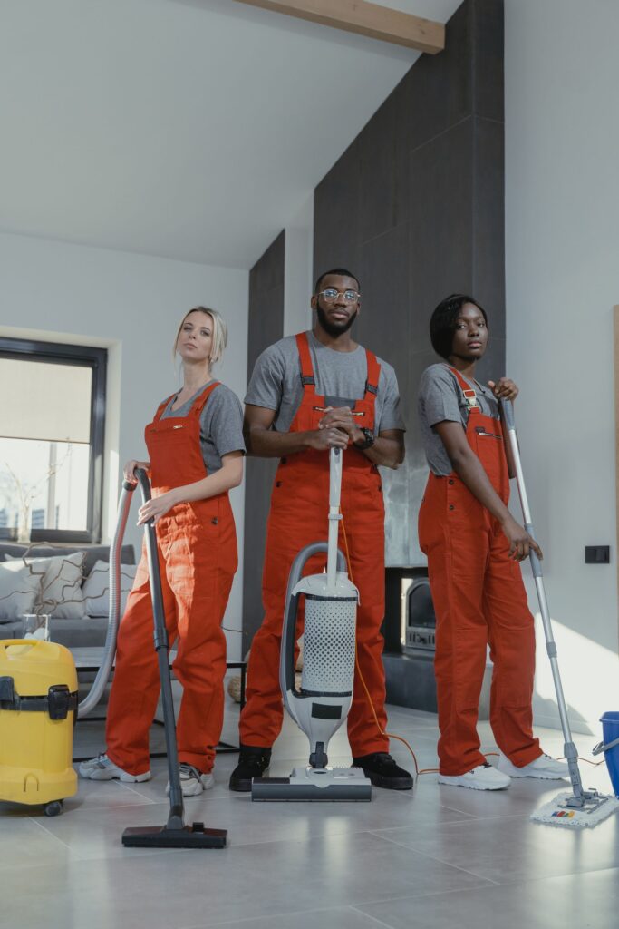 Trois employés de nettoyage en uniforme avec leur équipement