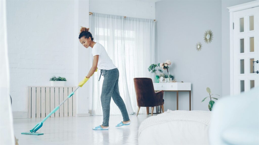 Femme qui lave le plancher d'un salon lumineux